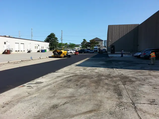 A newly paved commercial parking lot beside an industrial building