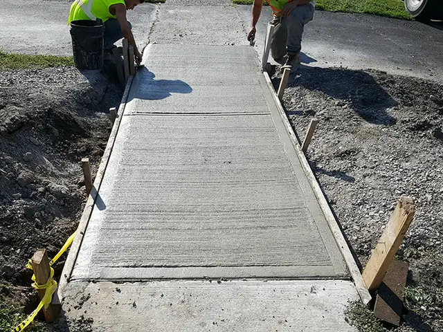 A crew finishing a new concrete sidewalk between forms