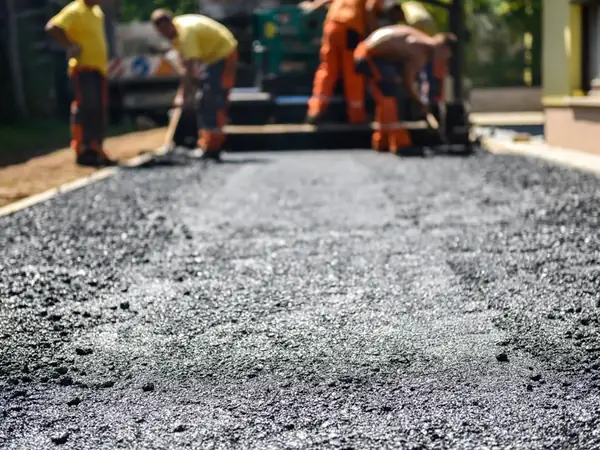 Crew raking hot asphalt by hand