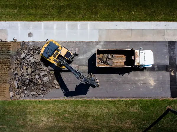 Overhead view of an excavator and truck removing old asphalt