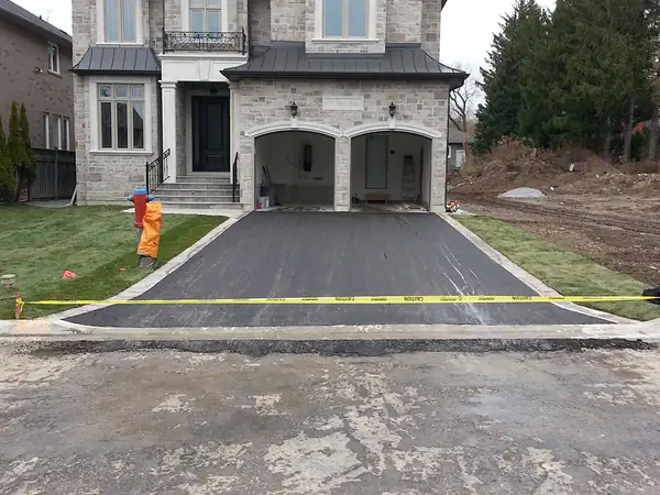 New asphalt driveway in front of a stone-front home