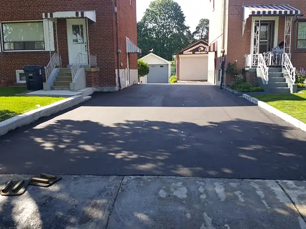 New asphalt driveway between two brick homes