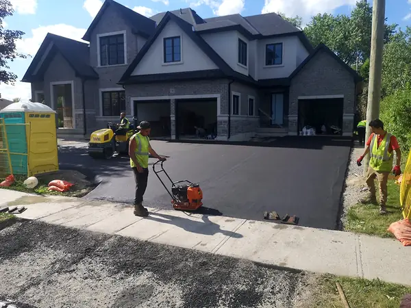 Crew finishing a new driveway at a large home