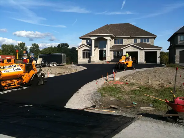 New curved driveway at a large home with paving equipment